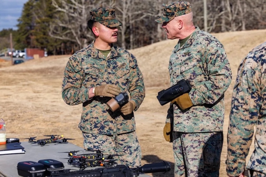 two men in fatigue talk while holding CUAS equipment