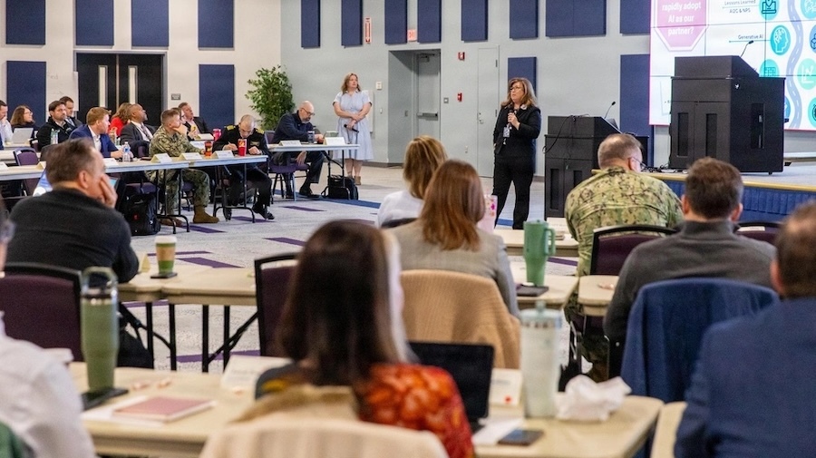 woman with a microphone addresses a group seat before her
