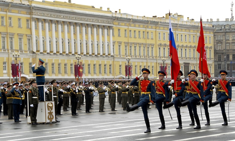 Russian troops parade in front of a yellow building