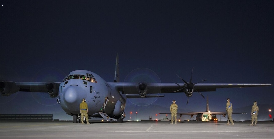 aircraft on tarmac at night with ground crew nearby