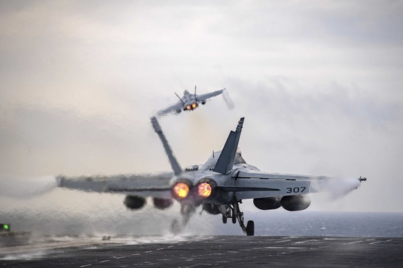 two jets taking off from an aircraft carrier