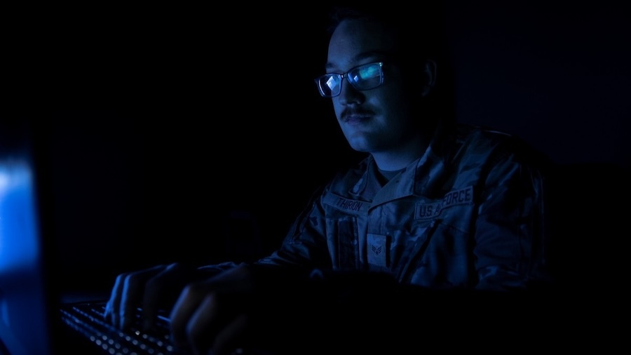 man in glasses works at computer in the dark