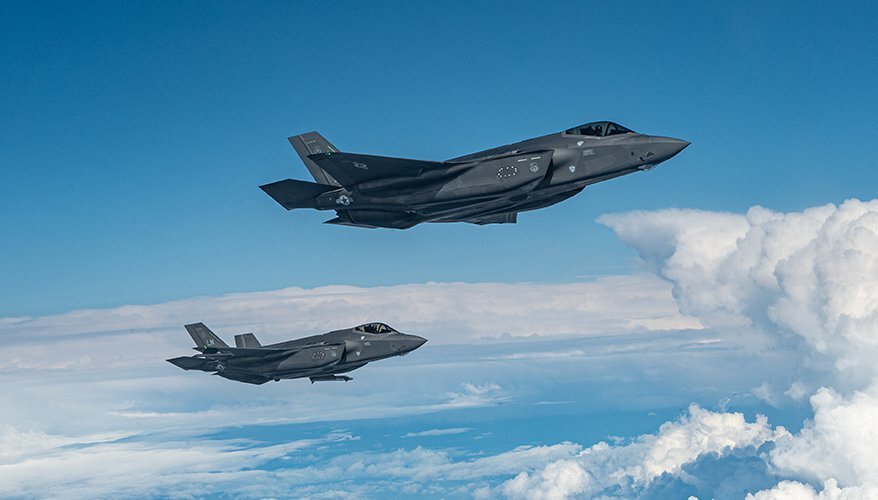 two aircraft against a blue sky with clouds