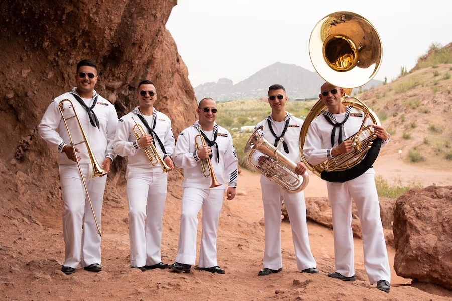 Navy band members standing next to a rock outcropping in the desert