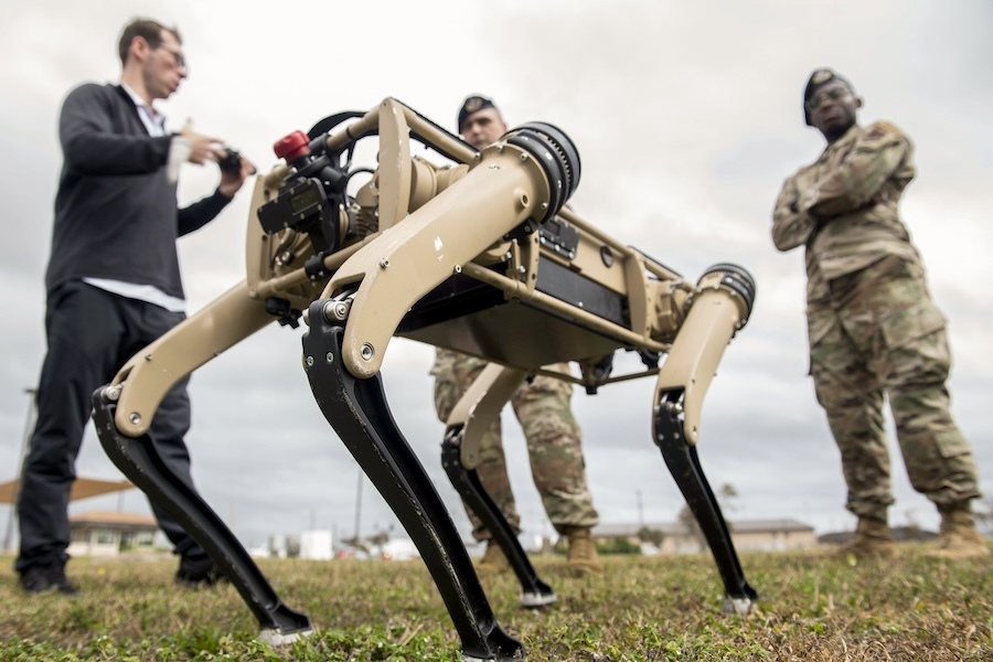 low shot of a four-legged drone, 3 men in background
