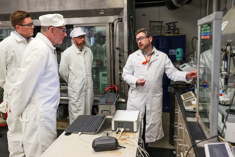 researchers in lab coats gather around a lab bench
