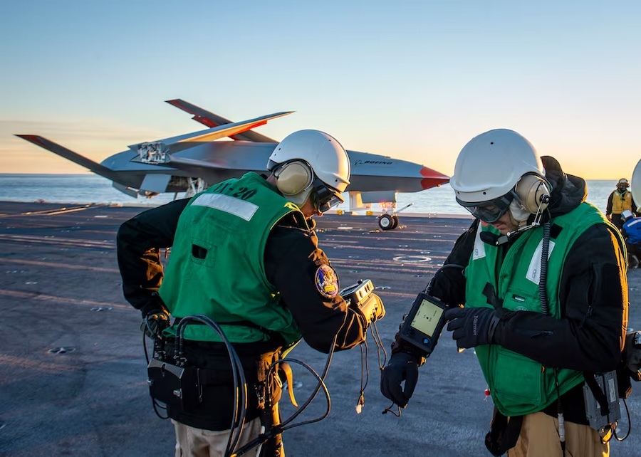 two technicians on an aircraft carrier, drone in background