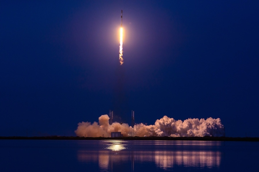 rocket lifitng off against a purple sky