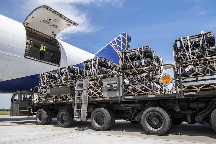 a truck stacked with cargo parked alongside a plane