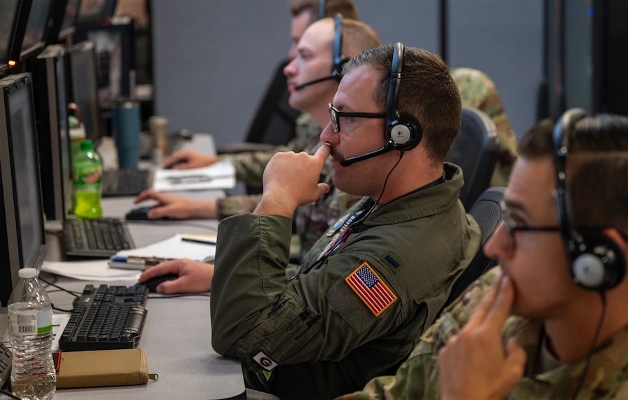airmen with headsets sit in front of computer screens