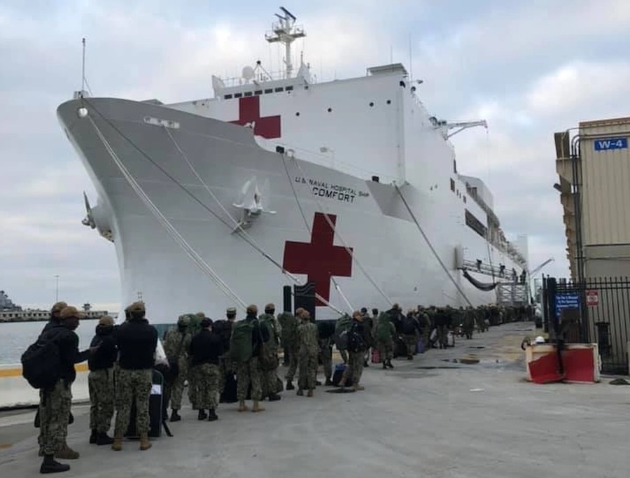 sailors lined up alongside a white Navy medical ship