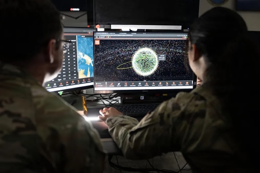 two people work in front of a computer screen showing space imagery