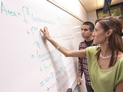 Dr. Erika Camacho works at a whiteboard with a student