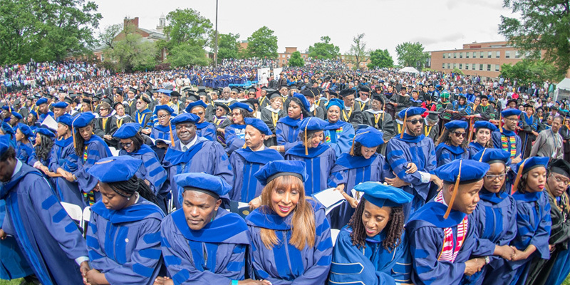 New degree recipients join hands at commencement at Howard University.