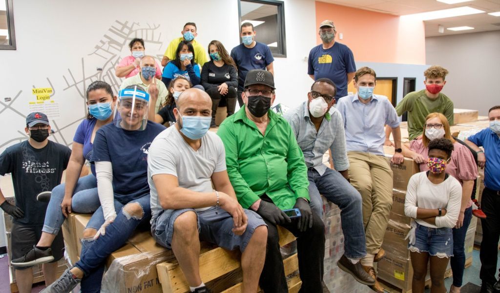 Over a dozen people pose for a group photo while wearing protective face coverings.