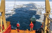Researchers at the back of a ship with a trowel