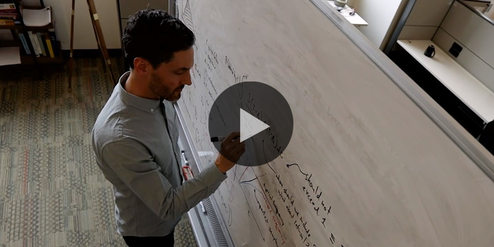 Daniel Larremore write equations at a white board.