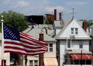 urban house with blue sky and american flag waving in foreground left