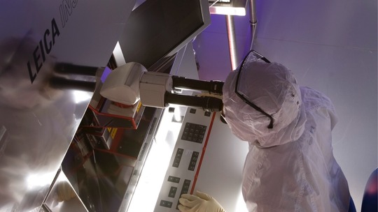 Technician in lab coat sitting at desk using water inspection tool