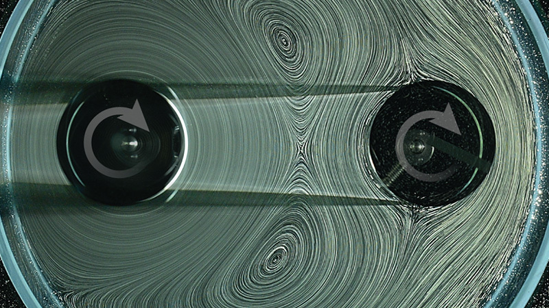 Two spinners inside a circular container and surrounded by liquid with bubbles.