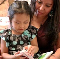Image shows an AI/AN woman and child reading together