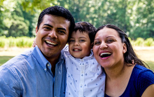 Hispanic parents and child smiling outdoors 