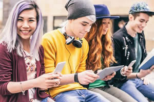 Image shows four teenagers using mobile devises