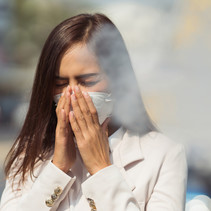 Image shows a Hispanic/Latina wearing a mask and shielding her face from smoke