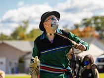 Image shows an American Indian man masked while at an outdoor event