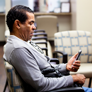 Image: Latino man using his mobile while in the doctor's waiting room