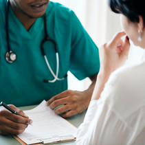 Image shows a Black health professional speaking with a female patient