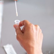 Image shows an at-home test swab and sample container. 