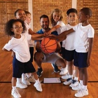 Image shows a diverse group of children and their basketball coach