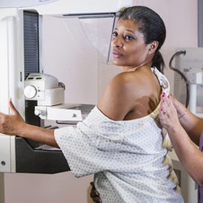 Image shows a Black woman getting a mammogram