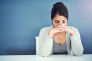 Image of a woman looking down with hands on head