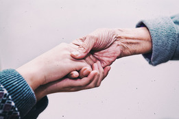 Close up image of young hands holding an old hand.