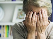 elderly woman with brusied finder hiding her face behind her hands