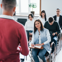 Person in a red shirt standing in front of a class.