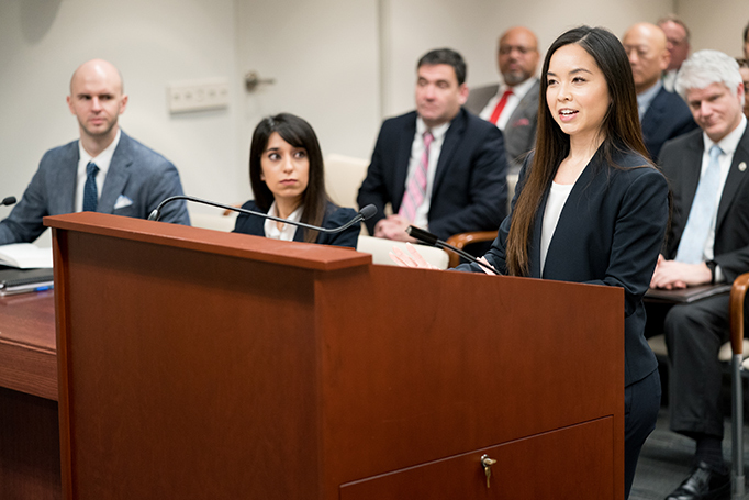 A female legal practitioner stands at a podium and makes an argument before the PTAB. 