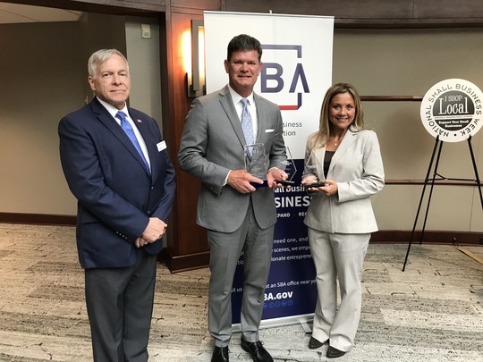 A group of people standing in front of SBA sign holding up awards