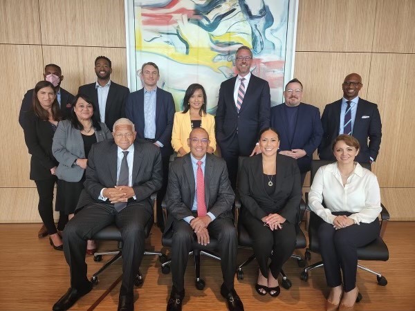 A group of people sitting and standing for a photo. 