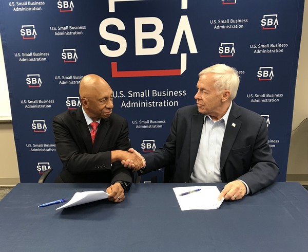 Executive director, Bob Dickerson (left) and Alabama District Director, Thomas Todt (right) shake hands with SBA logo in background.