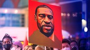 A crowd of people and a sign with a portrait of George Floyd.