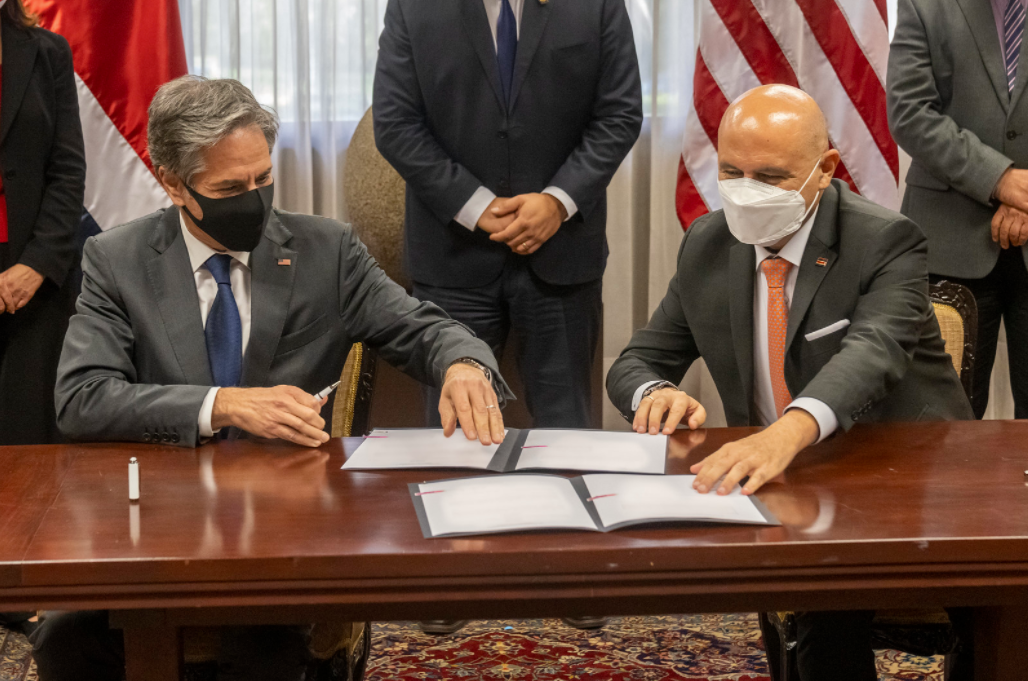 Secretary Blinken and Costa Rican Foreign Minister Solano sit at a table and sign official documents.