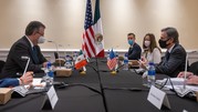  Secretary Blinken, Foreign Minister Ebrard, and others sit at a conference table; the flags of the USA and Mexico are in the background.