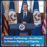 Secretary Blinken standing at a podium with the words 