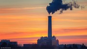 Smoke clouds coming from a factory smokestack against the backdrop of an evening sky.