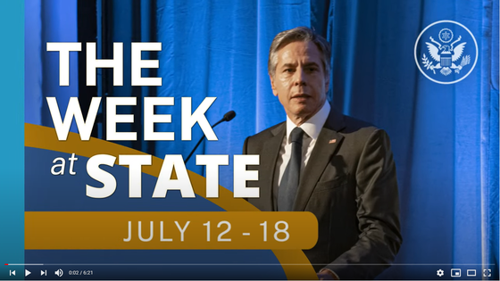 Screenshot of video of The Week At State, July 12-18, with Secretary Blinken speaking against a backdrop of blue curtains.