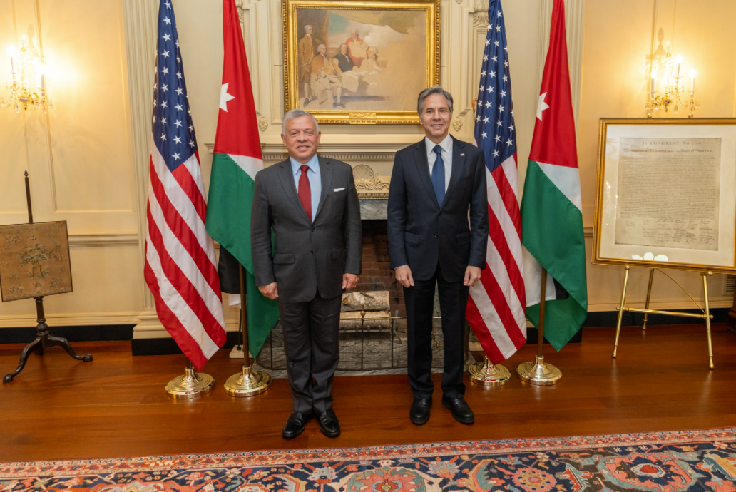 Secretary Blinken and King Abdullah II standing together with two American and Jordanian flags.