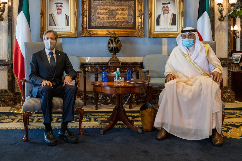 Secretary Blinken and the Kuwaiti Prime Minister sit in chairs in a meeting room. 